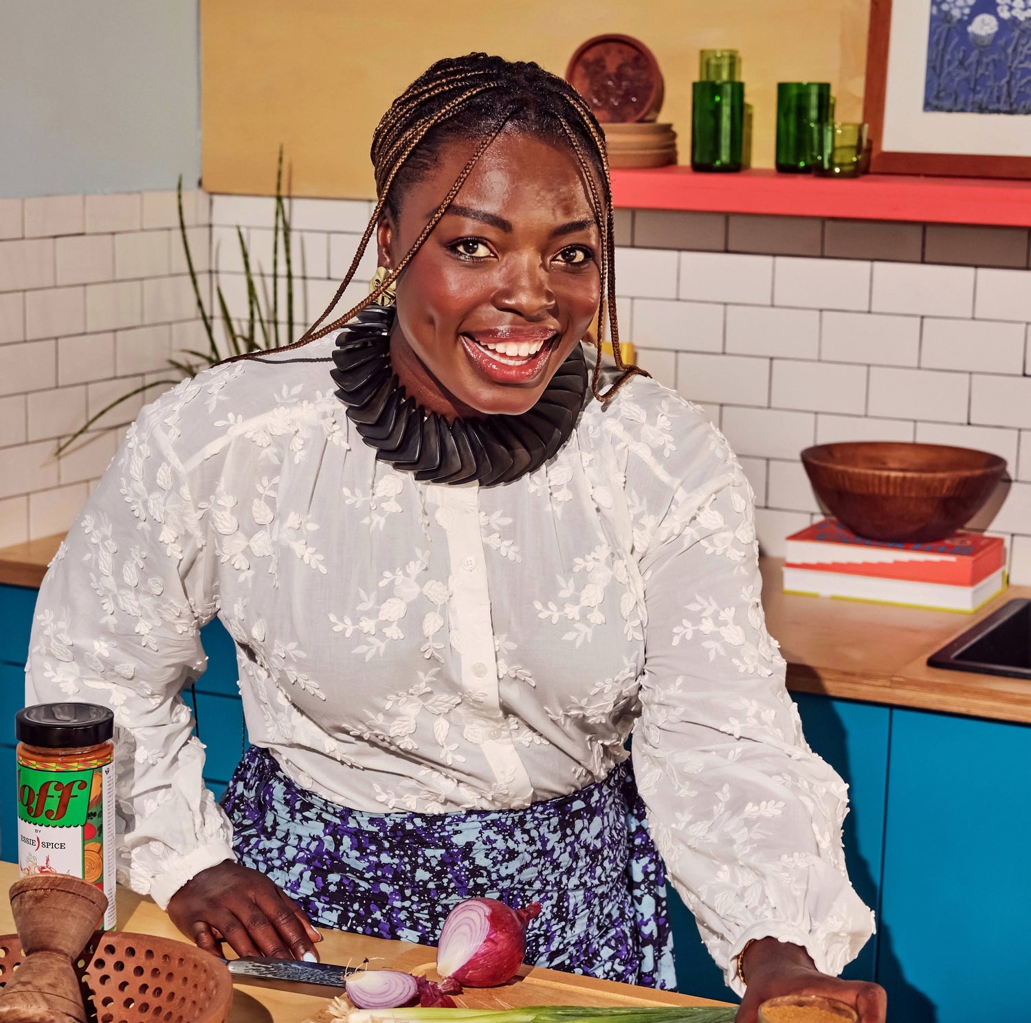 Person in a white blouse preparing food in a kitchen with colorful decor.